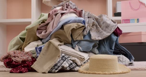 Mujer se arrastra fuera de una pila de ropa, en busca de sombrero, finalmente encontrarlo y lleva felizmente — Vídeos de Stock