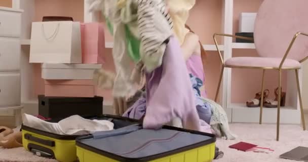 Vrouw proberen om koffer te sluiten met een heleboel dingen kleding. Reisconcept — Stockvideo