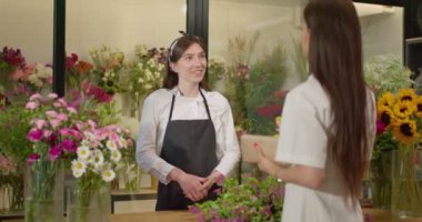 Dost canlısı kadın çiçekçi dükkandaki müşteri müşterisiyle konuşuyor. Çiçek Dükkanı Servisi