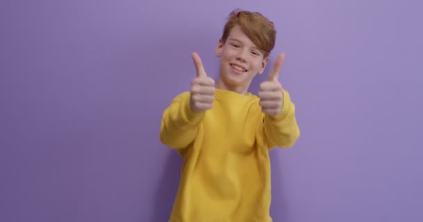 Thumbs up, nice sign. Portrait of young teen boy, student wearing yellow shirt posing — Video Stock