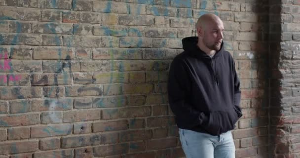 Junger kaukasischer Mann in schwarzer Kleidung steht an der Straße und wartet auf das Opfer, um ein Verbrechen zu begehen. — Stockvideo