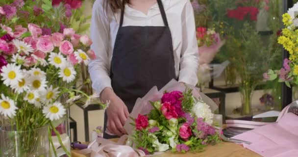 Florista moderno bem sucedido vestindo avental, criando belo buquê de flores coloridas — Vídeo de Stock