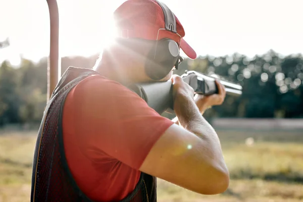 Visão traseira no belo tiro masculino no alvo em uma faixa de tiro ao ar livre — Fotografia de Stock