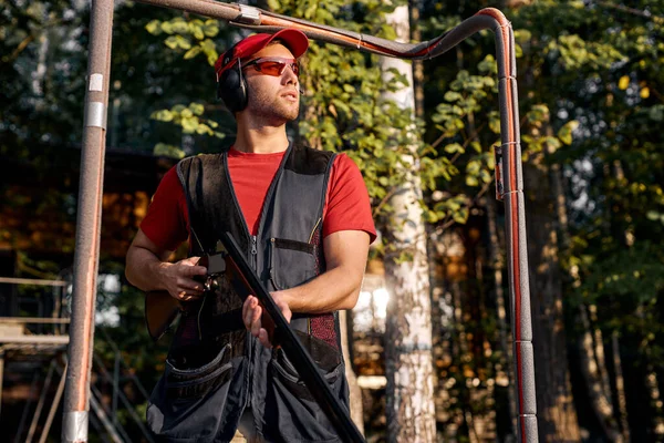 Confident man skeet shooting outdoors, shooting clay pigeon targets in outdoor range — Stock Photo, Image