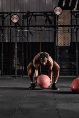 Strong and motivated athletic man exercise with medicine ball at health club or gym.