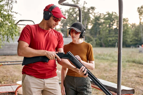 Hombre y mujer comprobando los detalles del arma antes de entrenar cargando arma al aire libre — Foto de Stock