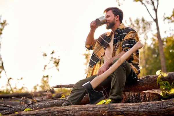 Giovane maschio esausto sedersi a bere tè dopo il taglio di legno, agnellino — Foto Stock