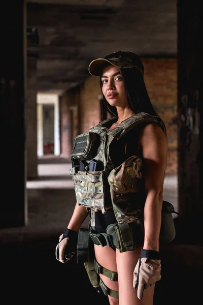 Femme confiante en équipement militaire posant à l'intérieur dans un bâtiment abandonné — Photo
