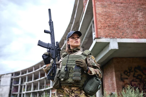 confident military woman with weapon in field, female in camouflage suit