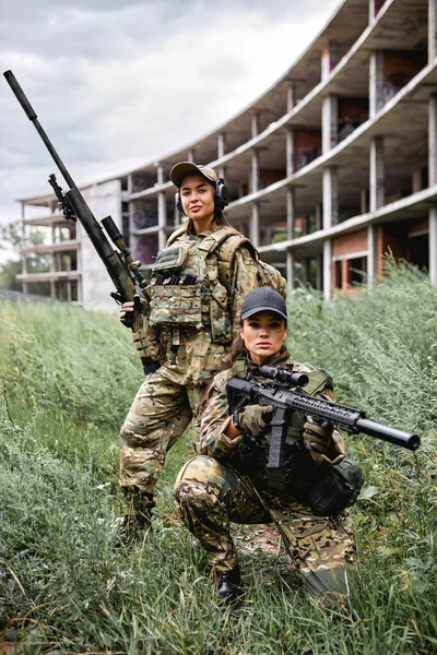 Två attraktiva kvinnor vänner i kamouflage hålla vapen innan krig kamp — Stockfoto