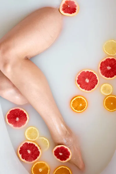 Жінка приймає молочну ванну з лимонами та апельсинами. Цитрусовий спа. Догляд за тілом. Відбілювання шкіри — стокове фото