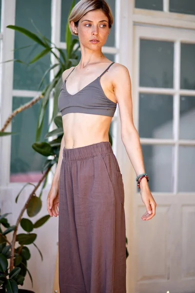 Slim fit woman is standing before yoga at home, preparing to meditate, wearing — Stock Photo, Image