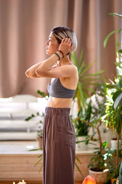 Evde yoga yapan, meditasyon yapmaya hazırlanan, giyinen zayıf bir kadının yan görüntüsü. — Stok fotoğraf