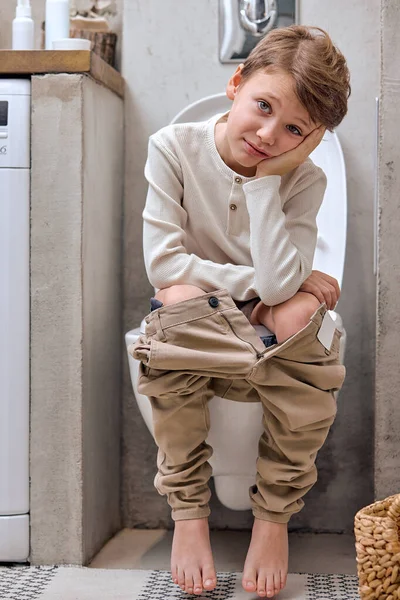 Anak laki-laki duduk di toilet dengan menderita sembelit atau wasir — Stok Foto