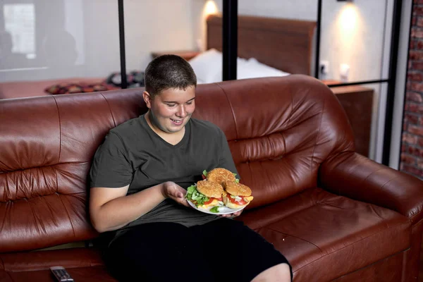 O rapaz está a comer demais. Criança gorda, dependência alimentar e problemas de comportamento. — Fotografia de Stock