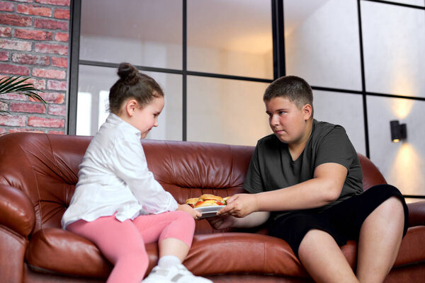 Толстый мальчик и девочка не могут делиться сэндвичами, голодные дети дома.