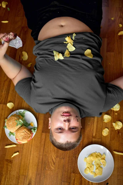 Top view on voracious teen boy surrounded by junk food, overeating concept — Stok fotoğraf