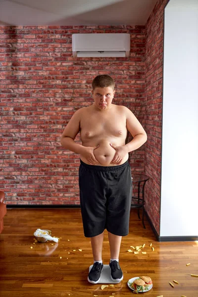 Fat upset boy after weighing. Teenage kid need to lose some excess weight. — Stok fotoğraf