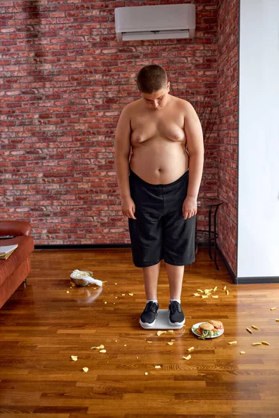 Dikke jongen teleurgesteld na het wegen en ontdekte dat hij aangekomen gewicht. — Stockfoto