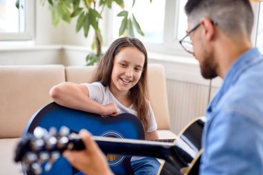 Erkek, gitar çalarak ve şarkı söyleyerek küçük kızla özel bir an geçiriyor.