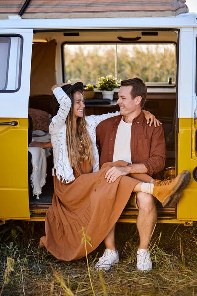Attractive young couple sitting inside of campervan while looking outside of the van — Stock Photo, Image