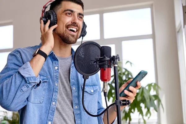 Positive Open-Minded Bearded Guy In Headphones поют песню в студии звукозаписи — стоковое фото
