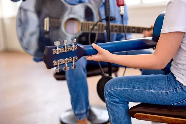 Cropped jeune homme enseigne à la petite fille mignonne à jouer de la guitare à la maison. mains en gros plan — Photo