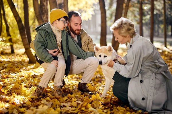 Adorable familia europea con perro mascota relajarse mientras pasea en el parque, en la temporada de otoño —  Fotos de Stock