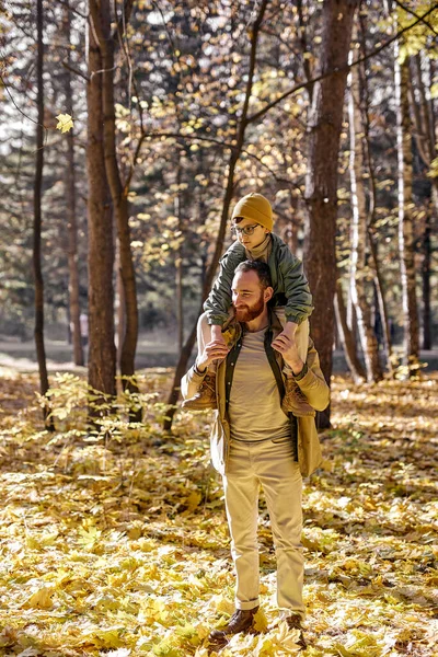 Menino e pai andando no parque de outono, homem segurando filho nos ombros — Fotografia de Stock