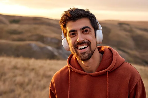 Excited man with headphones during morning jogging outdoors, in nature, having rest — Stock Photo, Image