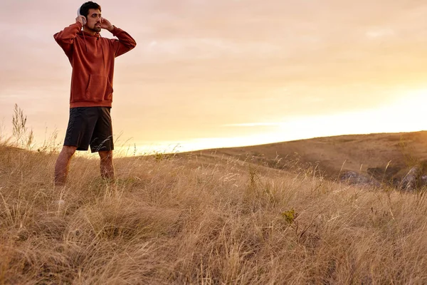 Genießen Sie das Leben. Mann steht auf Bergfeld und genießt den Sonnenaufgang, hört Musik — Stockfoto