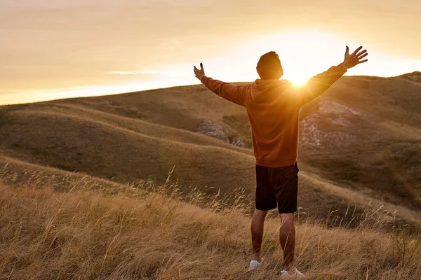 Ragazzo in cima alla montagna raggiunge per il sole durante l'alba, sentire la felicità, godersi la mattina — Foto Stock