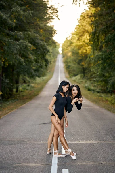 Professional ballerina ladies dancing in forest on road. Attractive young women — Stock Photo, Image