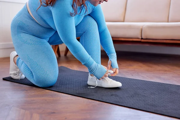 Bijgesneden vet vrouw zitten op mat strikken schoenen veters op tandvlees klaar oefening fitness oefening — Stockfoto