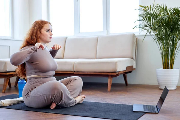 Spor giyim bölümünde şişman bir kadın yoga yapmadan önce kollarını esnetiyor. — Stok fotoğraf