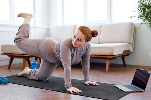 Şişman obez kadın evde spor egzersizleri yapıyor, dizüstü bilgisayar kullanarak. kilo kaybı — Stok fotoğraf