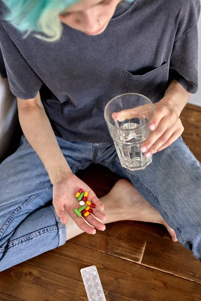 Przycięta kobieta siedząca na podłodze w domu, przedawkująca tabletki, przygnębiona kobieta. — Zdjęcie stockowe