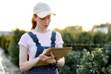 Çiçek açan, bahçıvanlık yapan ve insanların konseptiyle klipboda yazan işçi kadın..