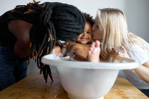 Feliz bebé riendo tomando un baño mientras los padres la besan. niño pequeño en el baño. — Foto de Stock