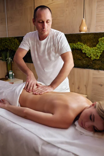 Masaje y cuidado corporal. Mujer joven con piel bronceada o miel recibiendo masaje relajante por hombre —  Fotos de Stock