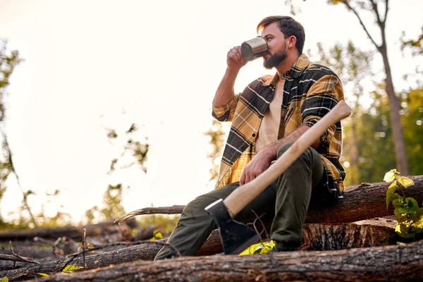 Joven leñador sentarse a beber té descansando después de cortar árboles —  Fotos de Stock