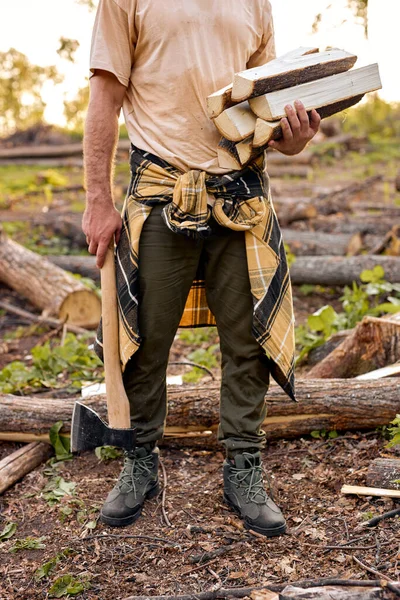 Cortado macho leñador trabajador sosteniendo leña en las manos, al aire libre en el bosque en el día —  Fotos de Stock