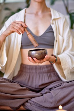 Tibet kâsesini tutan ve eline yapışan genç yogin kadının yakın çekimi.