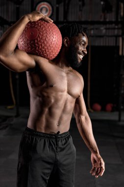 Güçlü Afro-Amerikan atletik adam fitbol ile fonksiyonel antrenman yapıyor.