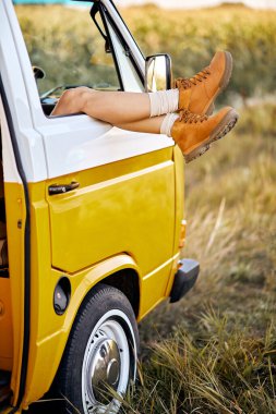 Kırbaçlanmış kadın turuncu çizmeli, sarı minibüslü, tarlada, doğada