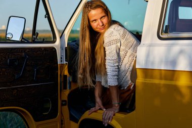 Genç bir kadın yolculuk sırasında mini minibüsün kapısından dışarı bakar, derin derin düşünür.