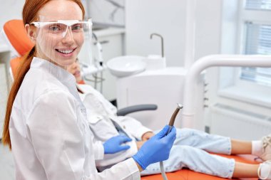 Sağlıklı dişler ve gülümseme. Diş hekiminin portresi, elinde diş matkabı tutuyordu.