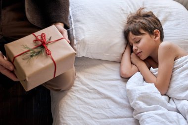 Noel sabahı konsepti. Yatakta yalan söyleyen çocuğun yanında tanınmayan bir adam yatıyor.