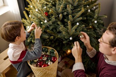 Sevimli, genç, beyaz bir baba ve küçük bir oğul Noel ağacını birlikte süsleyin.