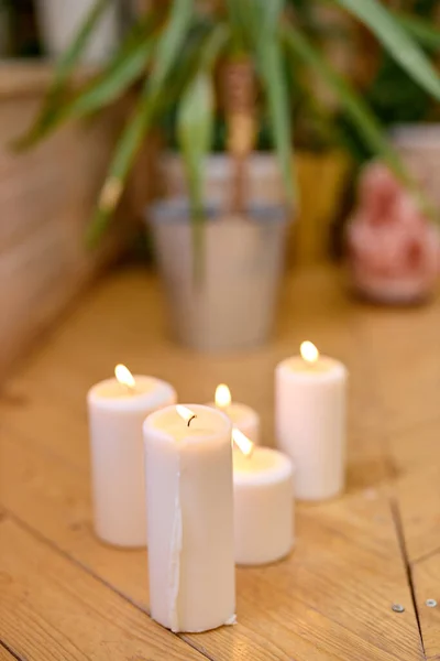 Close-up foto van kaarsen op houten vloer thuis, plant in pot op de achtergrond — Stockfoto